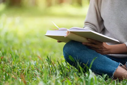 کودک در حال خواندن کتاب در کنار والدین خود