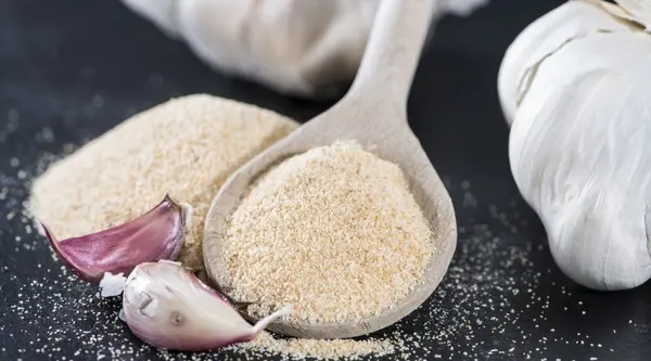 پودر سیر در ظرف شیشه‌ای با قاشق چوبی