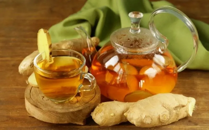 فنجان دمنوش زنجبیل تازه با ریشه‌های تازه در یک ظرف چینی