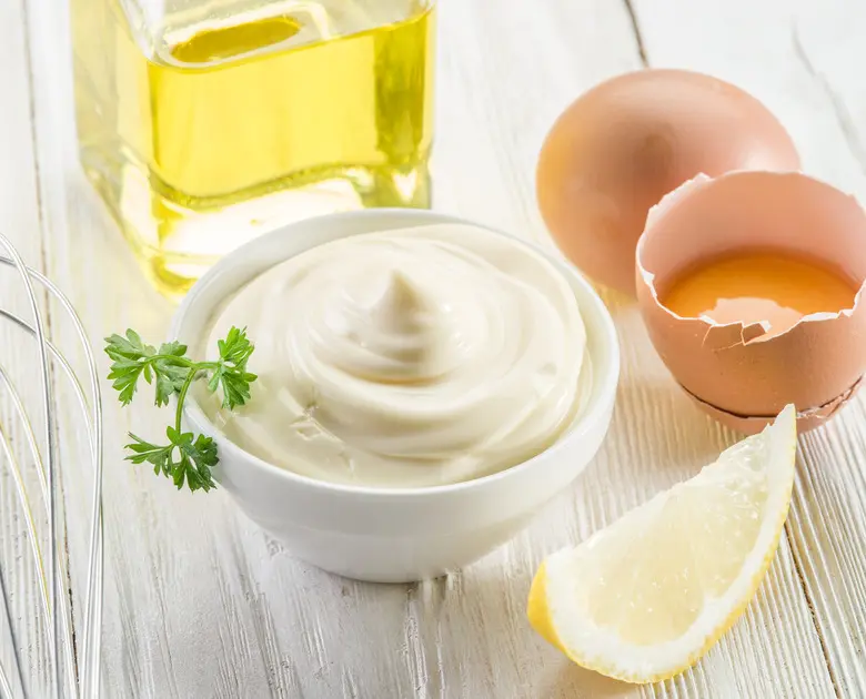 مایونز در یک ظرف شیشه‌ای با لöffel چوبی و سالاد در کنار آن