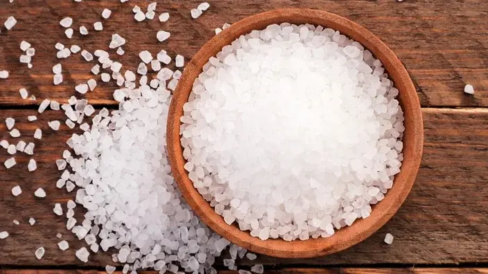 قاشق چایخوری نمک روی میز سفید با زمینه روشن