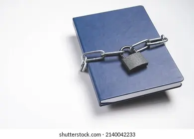 یک کتاب قفل شده با کلید در کنار آن، نشان‌دهنده محافظت فیزیکی از کتاب