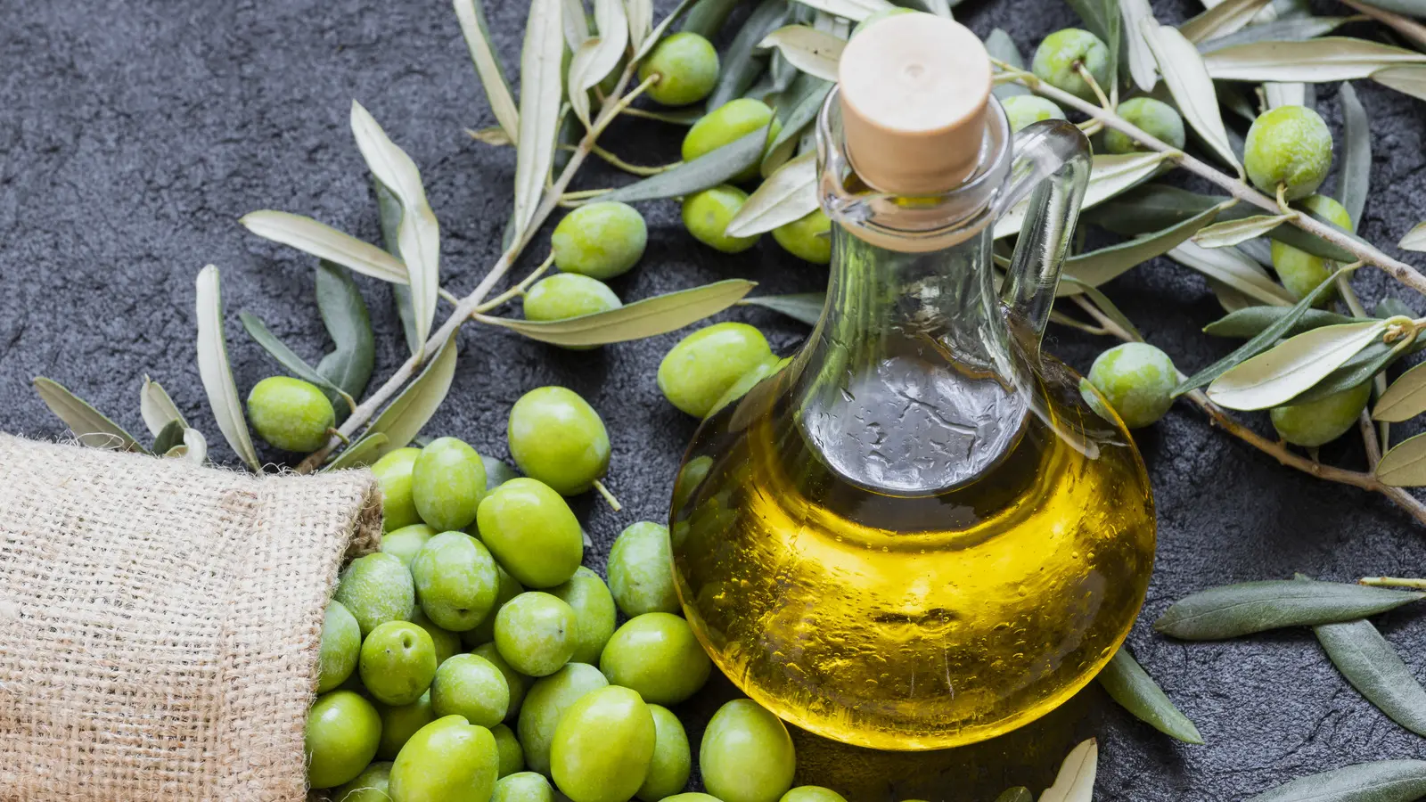 میوه زیتون تازه و روغن زیتون در بطری شیشه‌ای