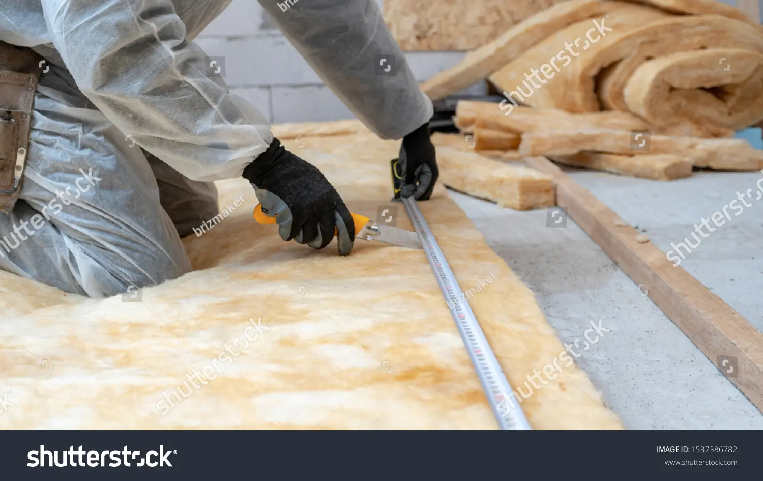 کارگر متخصص در حال اندازهگیری و آمادهسازی سطح دیوار برای عایقکاری