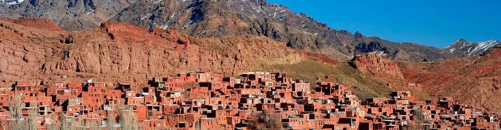 منظره کلی روستای ابیانه با خانه‌های سرخ رنگ و قلعه تاریخی در پس‌زمینه