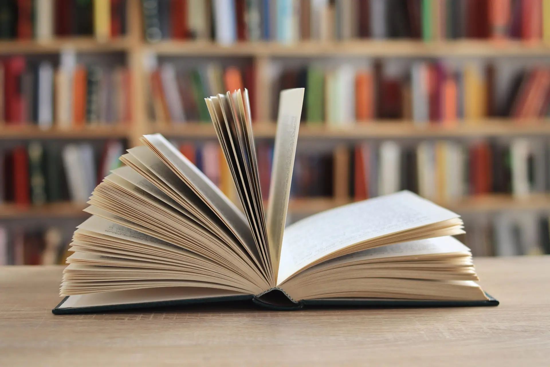 یک فرد در حال مطالعه با کتاب و دفتر یادداشت
